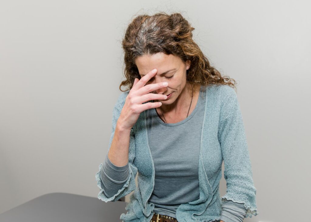 Woman holding her head, appearing to experience a headache.